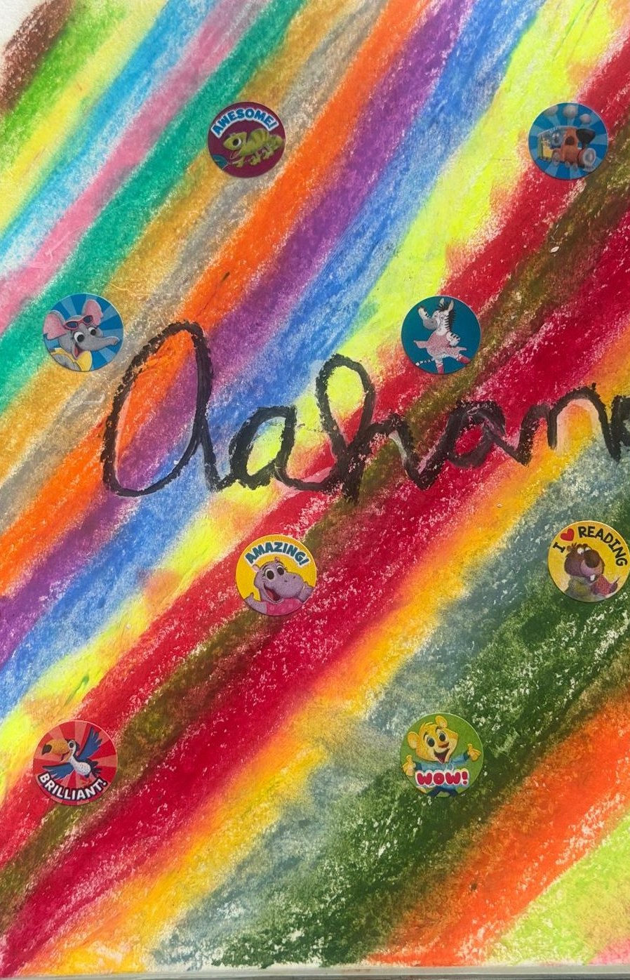The name Aahana written across bright diagonal rainbow stripes with fun reward stickers — oil pastel drawing by Aahana